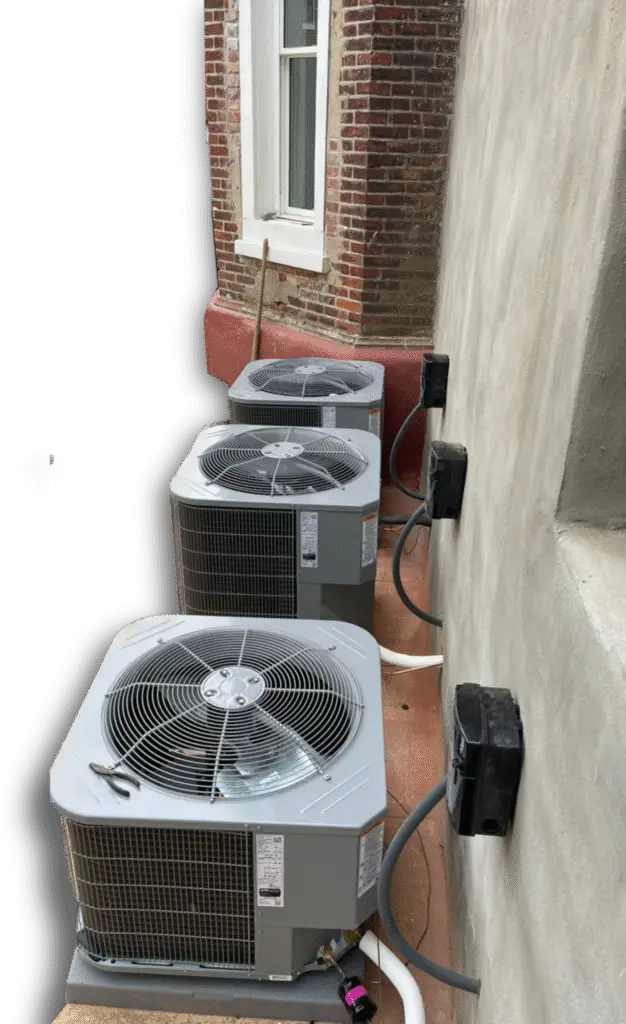 Wallingford, PA Three outdoor air conditioning units are installed in a row on a narrow ledge next to a brick and stucco building, ready for servicing air conditioning or commercial air con repairs by a skilled air conditioning repairman.