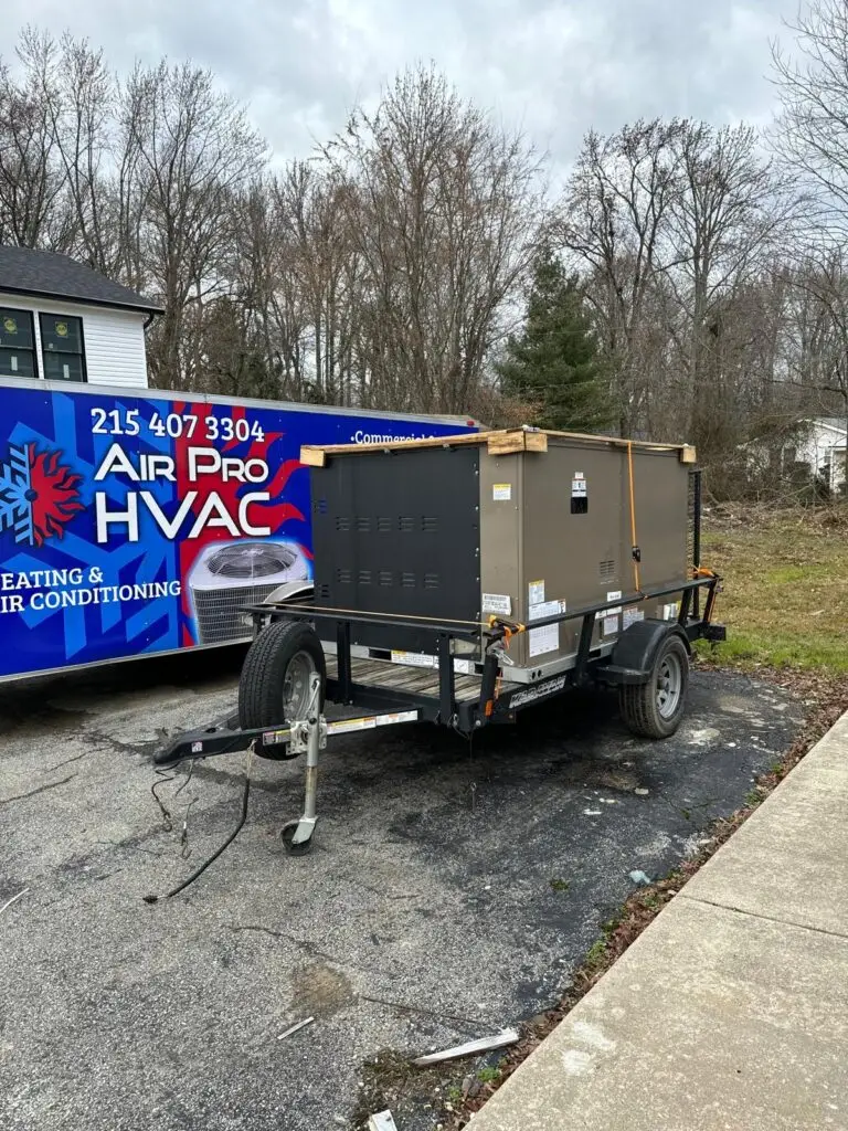 Upper Darby, PA A large HVAC unit sits on a trailer in a parking lot next to an Air Pro HVAC service van, where an air conditioning repairman is busy servicing air conditioning on a cloudy day.