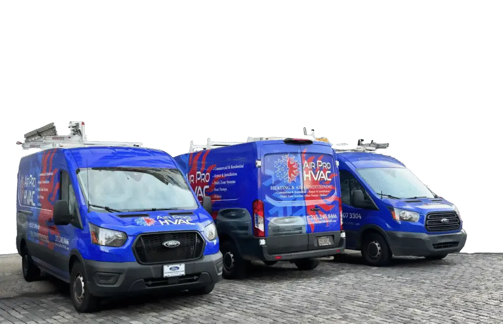 Three blue HVAC service vans with Air Pro HVAC branding, ready for commercial air con repairs, are parked side by side on a cobblestone surface, equipped with ladders on their roofs.