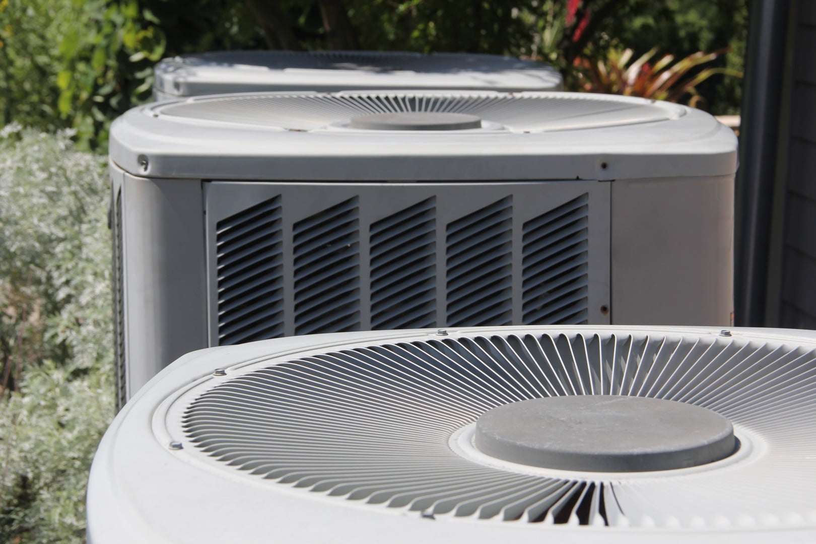 A certified hvac installer measuring clearance around a residential outdoor AC condenser unit during a relocation assessment in a suburban backyard